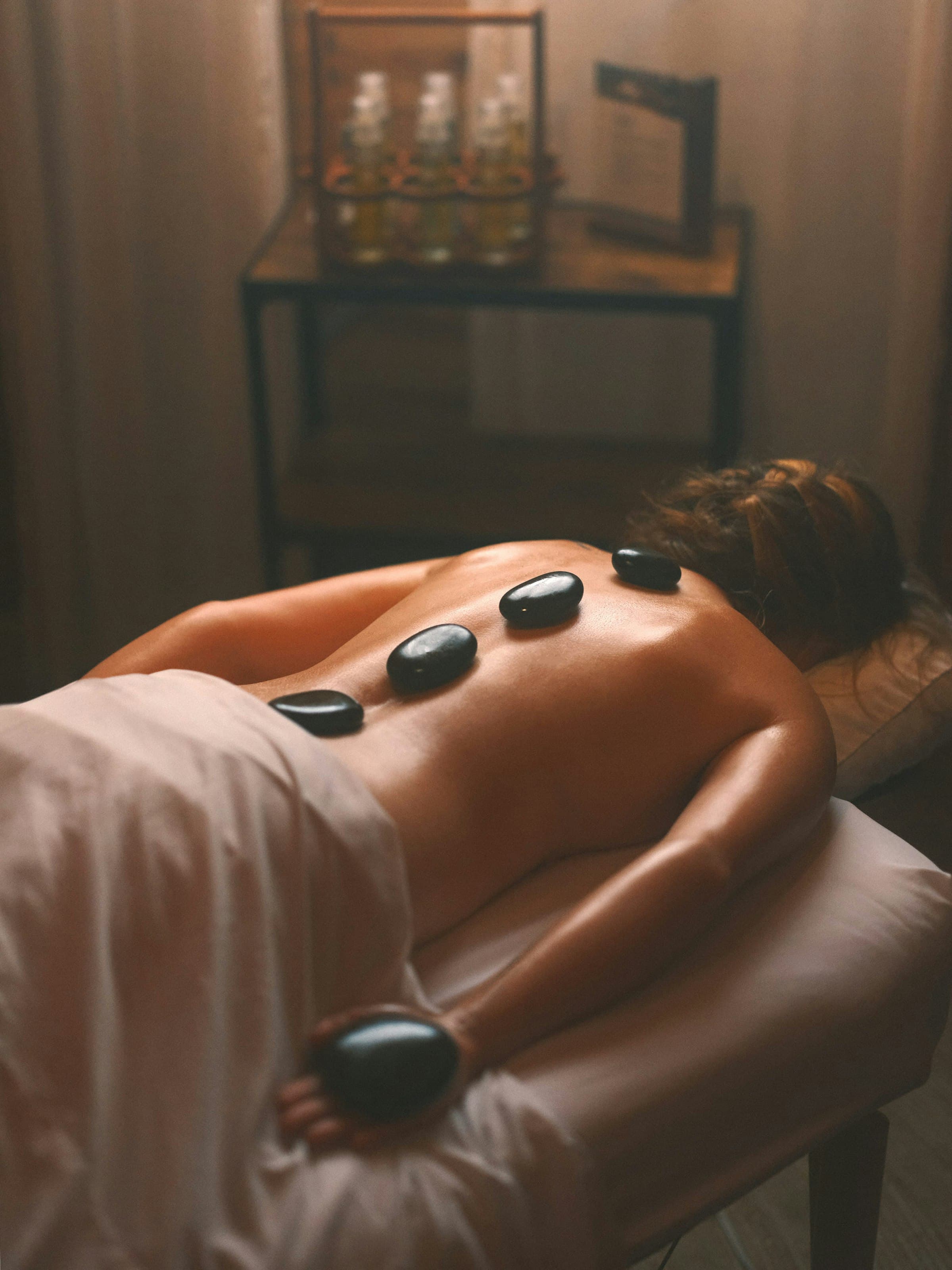Soin aux pierres chaudes sur une table de massage, ambiance tamisée